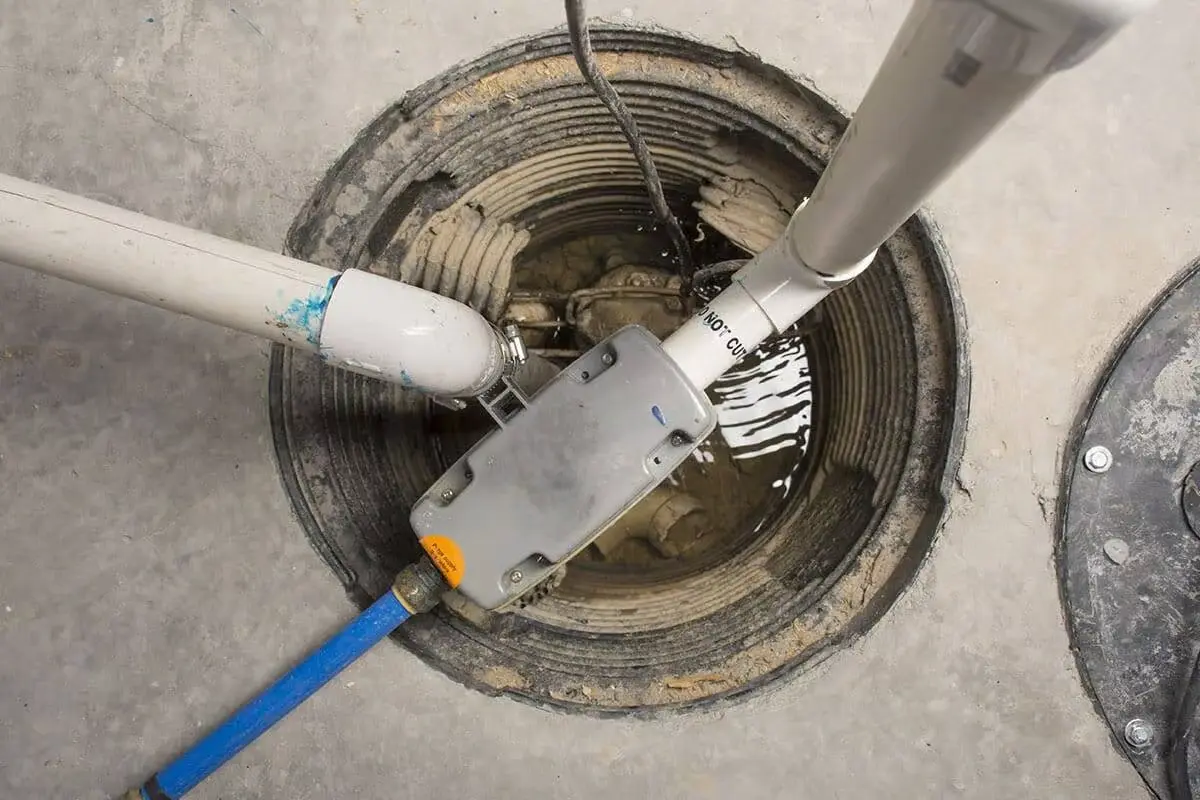 Overhead view of a professional sump pump installation in a Bloomington basement pit with PVC discharge lines and check valve